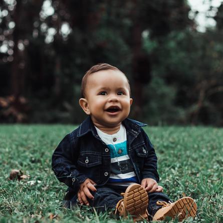 Smilende baby model poserer på græs
